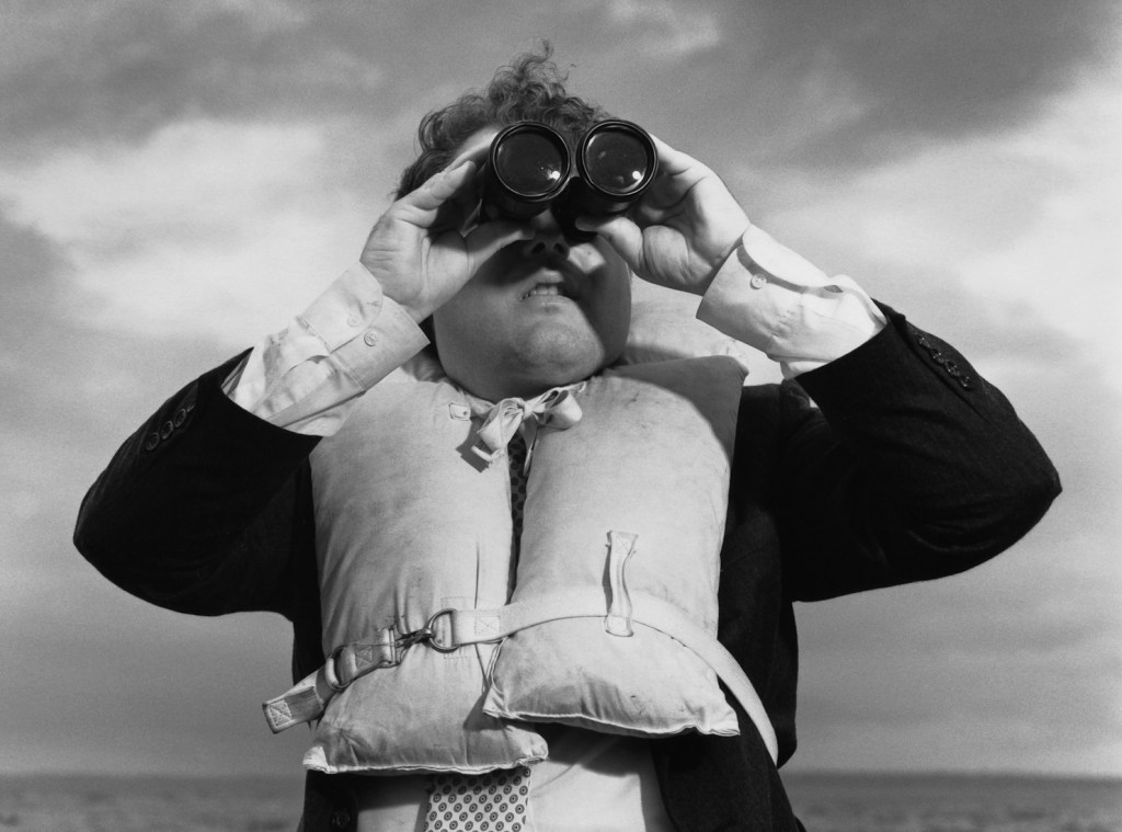 A Businessman searches with a pair fo binoculars